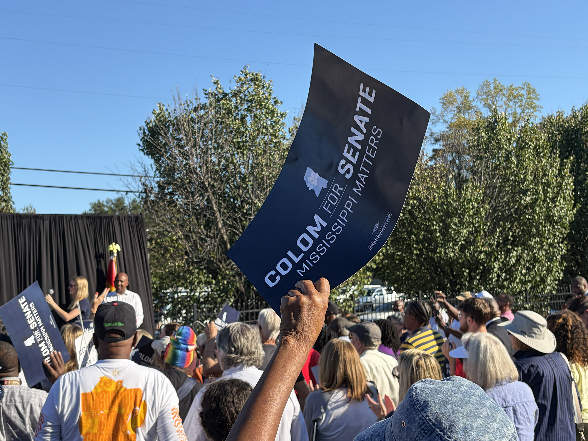 Supporter waves a “Colom for Senate” campaign sign at a rally with Sen. Raphael Warnock in Jackson, Mississippi. 